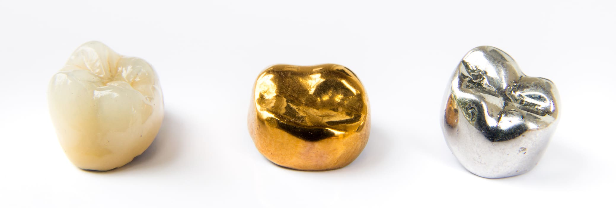 Dental ceramic, gold and metal tooth crowns on white background.