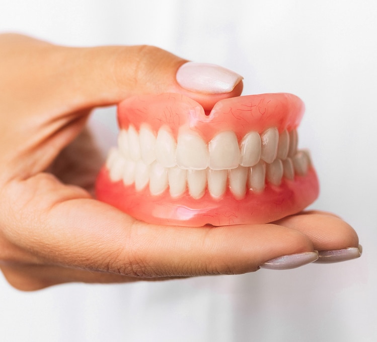 Woman's hand holding Dentures
