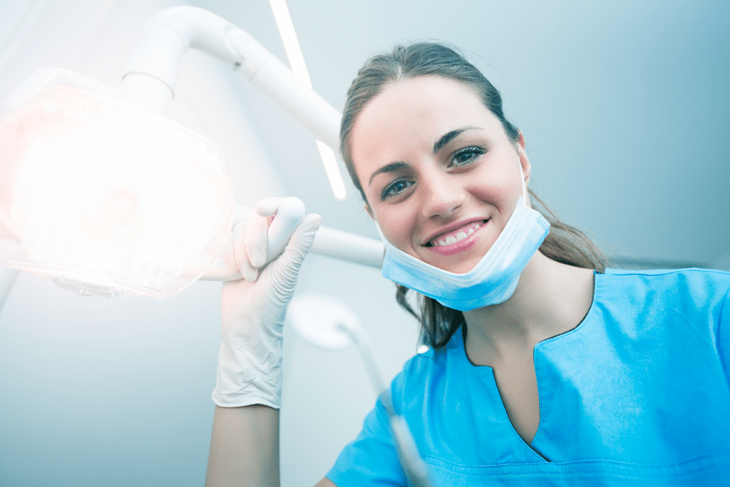 dental hygienist looking at patient and adjusting the light above during dental checkup