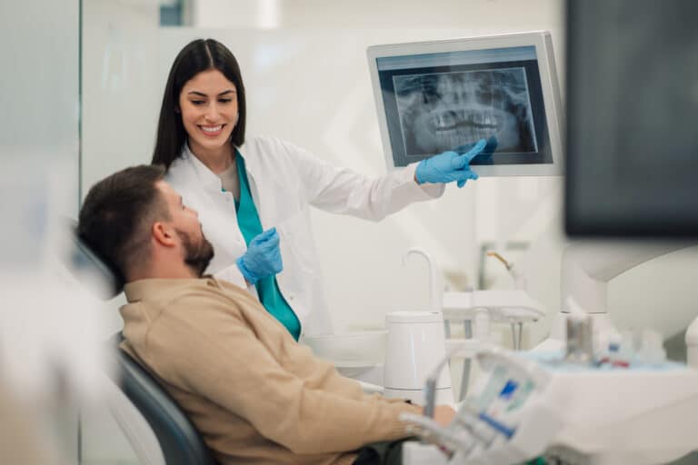 Female dentist showing a teeth x-ray to a male patient in a dental clinic. Periodontist appointment