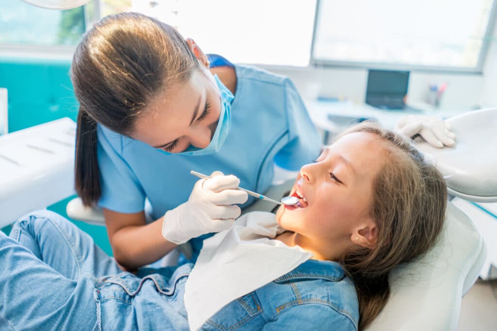 Kids dental extraction. Beautiful girl at the dentist getting a check up on her teeth - pediatrics dental care