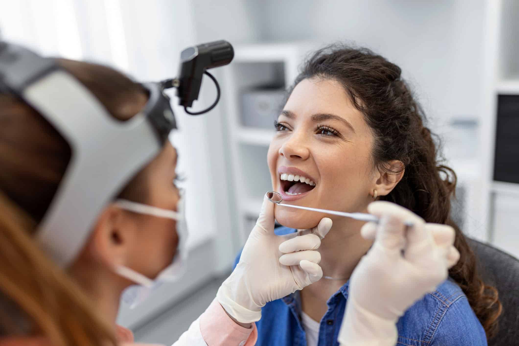 Beautiful curly haired woman has mouth examined at the dentist in an oral cancer screening