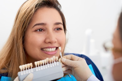 Shades being held up to a dental female patient's mouth for dental veneers